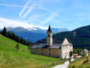 Kloster Maria Waldrast eingebettet in grüne Wiesen, im Hintergrund der Olperer Gletscher